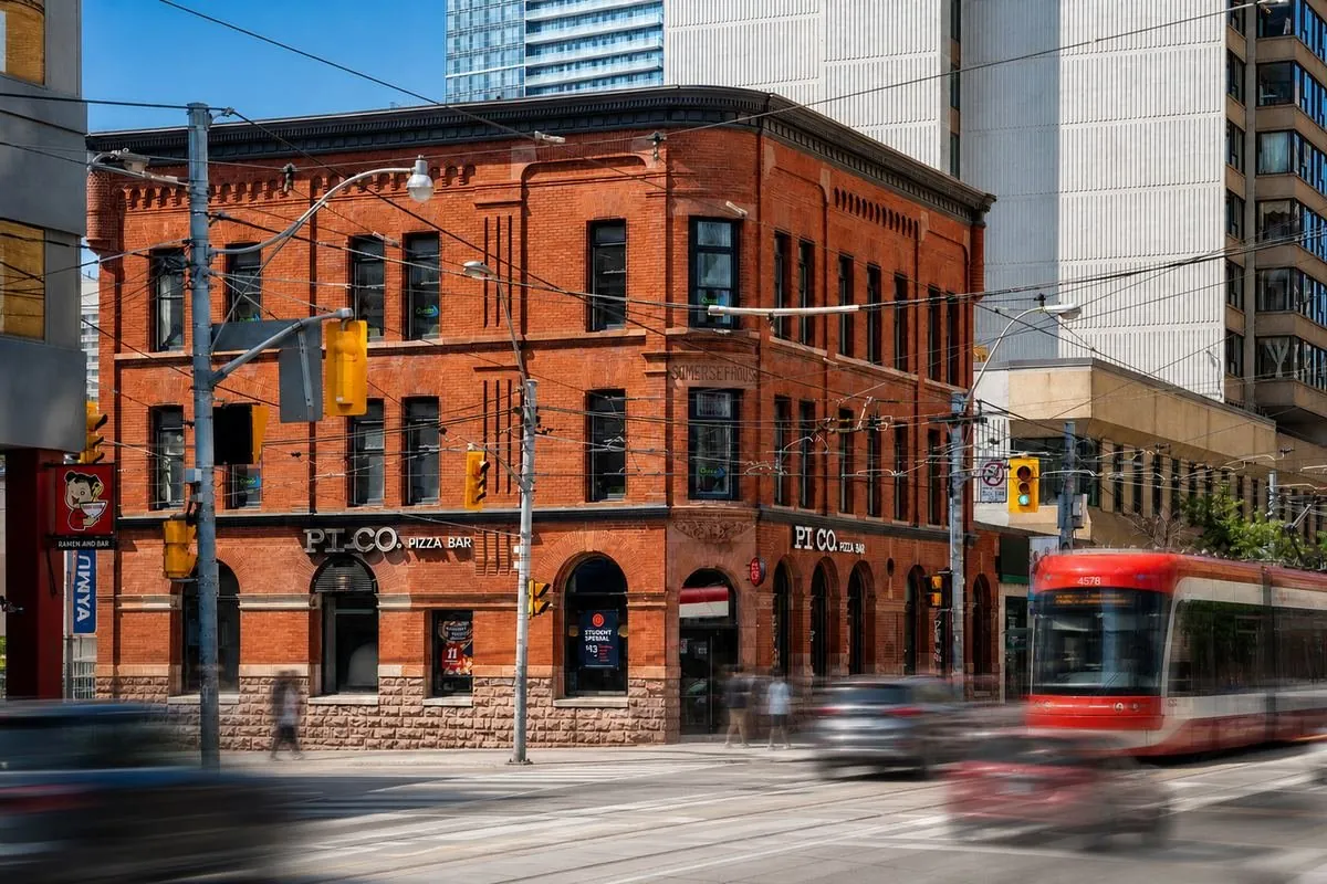 Red brick heritage building at a Toronto intersection with a streetcar passing
